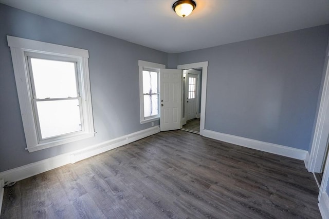 spare room with baseboards and dark wood finished floors