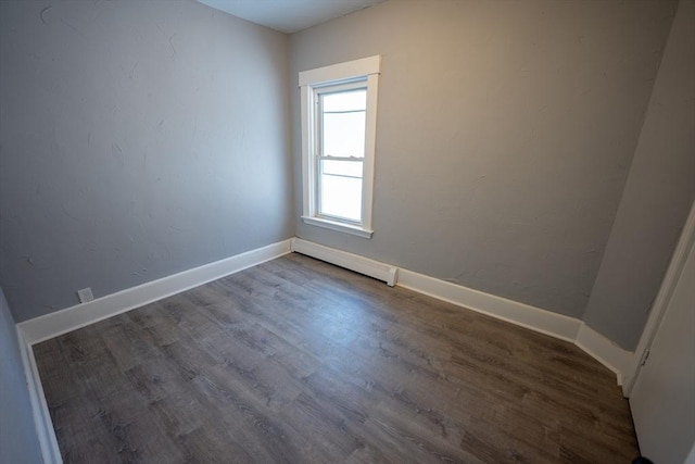 spare room with baseboards, baseboard heating, and wood finished floors