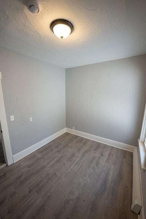 spare room with dark wood-style floors, a textured ceiling, and baseboards