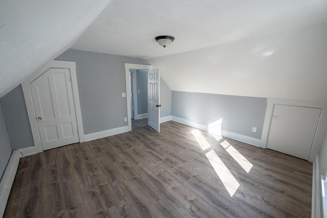 additional living space featuring lofted ceiling, baseboards, baseboard heating, and wood finished floors