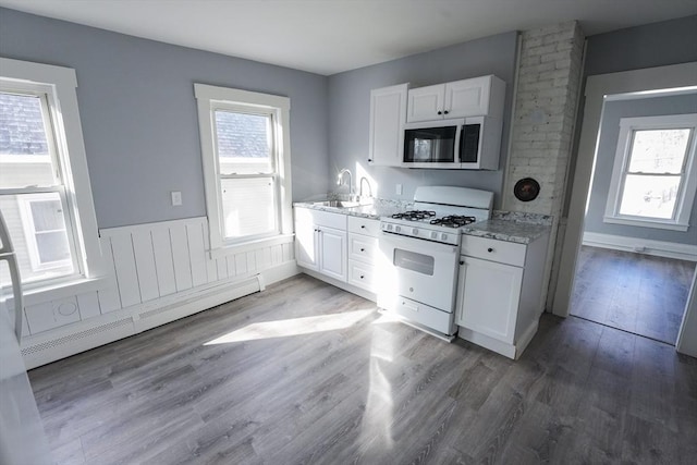 kitchen with white gas range oven, light wood-style flooring, stainless steel microwave, baseboard heating, and a sink