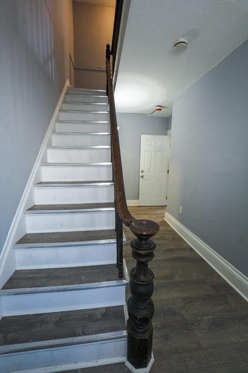 staircase featuring baseboards and wood finished floors