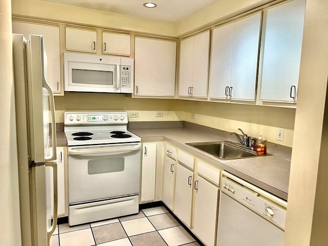 kitchen featuring white appliances, cream cabinetry, light tile patterned floors, and sink