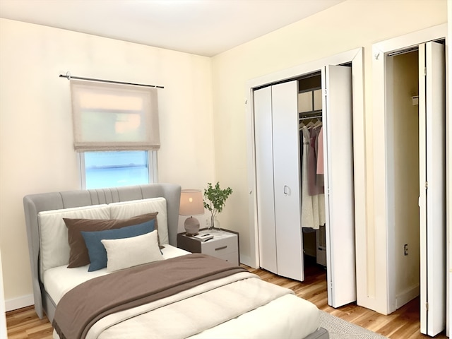 bedroom with light hardwood / wood-style flooring and multiple closets