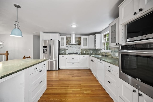 34 Clubhouse Ln, Natick, MA 01760 - kitchen featuring appliances with stainless steel finishes, wall chimney exhaust hood, tasteful backsplash, light wood-type flooring, and hanging light fixtures