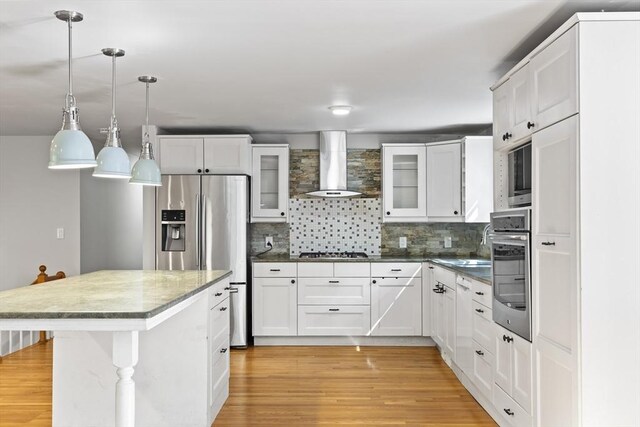 34 Clubhouse Ln, Natick, MA 01760 - kitchen featuring wall chimney range hood, stainless steel appliances, light wood-style floors, tasteful backsplash, and a center island