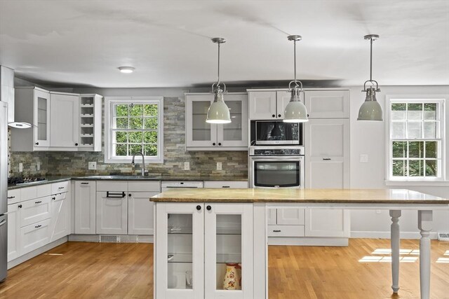34 Clubhouse Ln, Natick, MA 01760 - kitchen featuring appliances with stainless steel finishes, light wood-type flooring, tasteful backsplash, and white cabinets