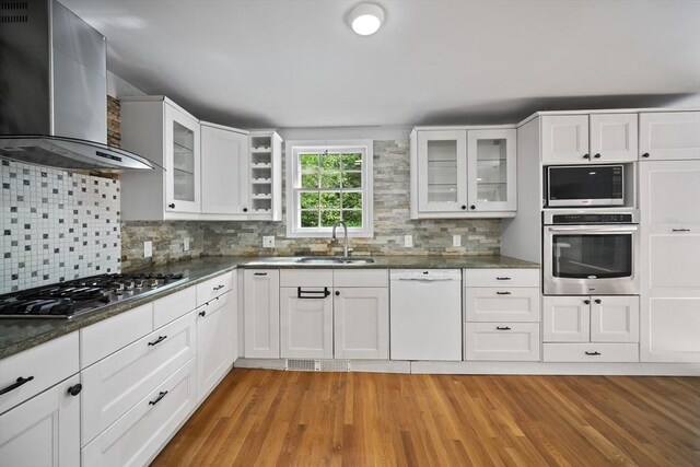 34 Clubhouse Ln, Natick, MA 01760 - kitchen with wall chimney exhaust hood, appliances with stainless steel finishes, light wood-style floors, decorative backsplash, and white cabinets