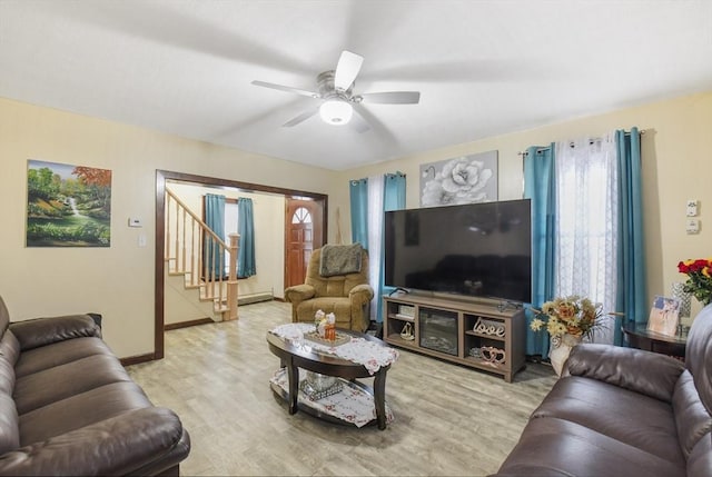 living area with a ceiling fan, baseboards, light wood-style floors, and stairs