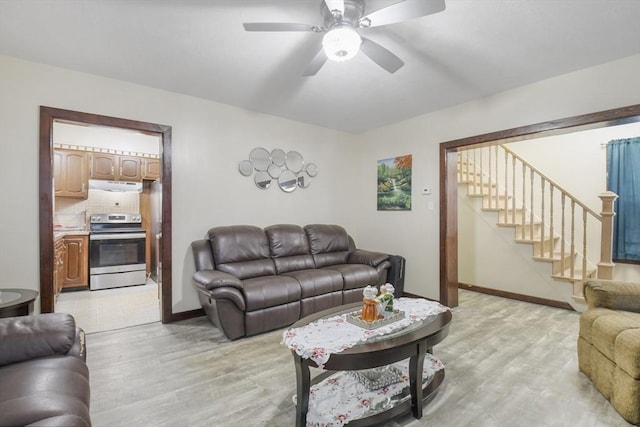 living room with stairway, baseboards, ceiling fan, and light wood finished floors