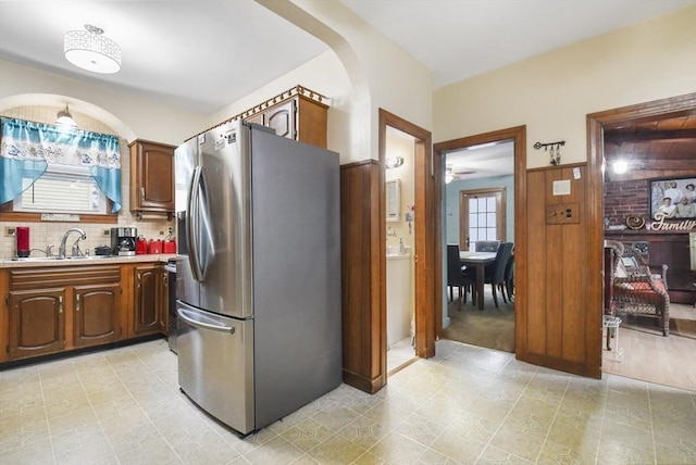 kitchen featuring backsplash, light countertops, stainless steel refrigerator with ice dispenser, a ceiling fan, and a sink