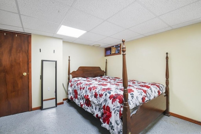 bedroom featuring a paneled ceiling and baseboards