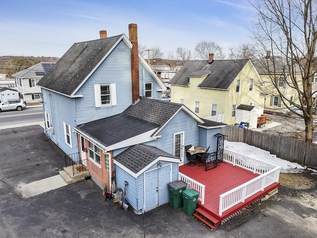 back of house with an outbuilding, a deck, fence, a residential view, and a storage shed