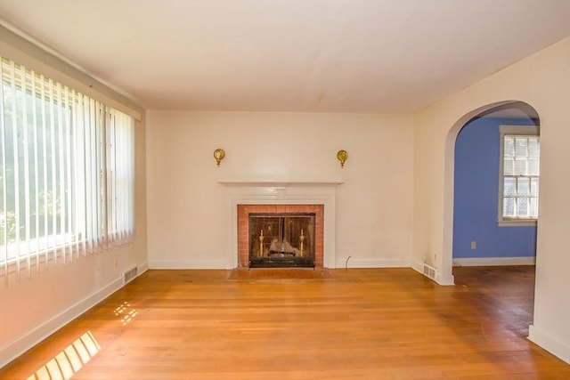112 Harmon Ave, Springfield, MA 01118 - unfurnished living room featuring arched walkways, healthy amount of natural light, light wood finished floors, and a fireplace