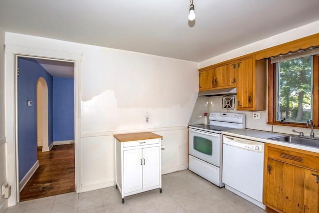 112 Harmon Ave, Springfield, MA 01118 - kitchen with white appliances, under cabinet range hood, light countertops, arched walkways, and brown cabinetry