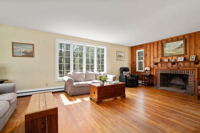 living area featuring a fireplace, a baseboard heating unit, wood finished floors, and wood walls
