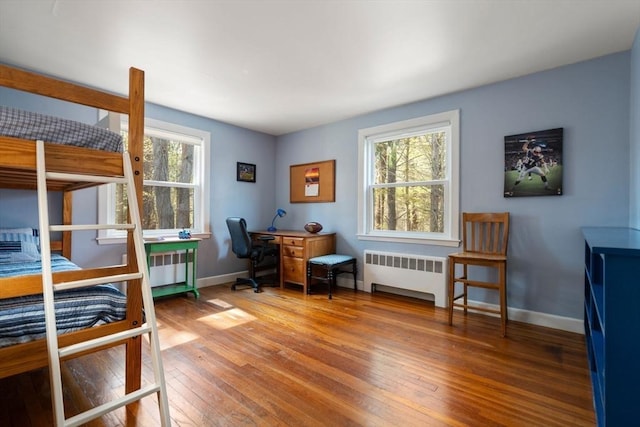 bedroom with radiator heating unit, hardwood / wood-style flooring, baseboards, and an office area
