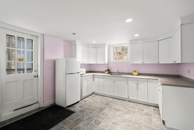 kitchen featuring white appliances, a sink, white cabinetry, recessed lighting, and stone finish flooring