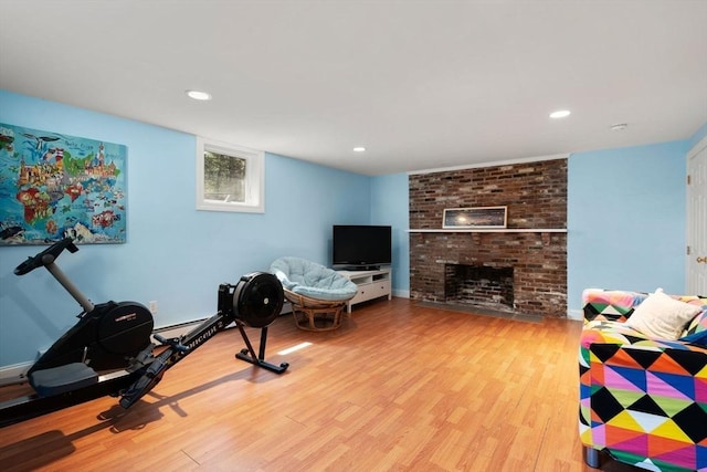 living room with wood finished floors, a brick fireplace, and recessed lighting