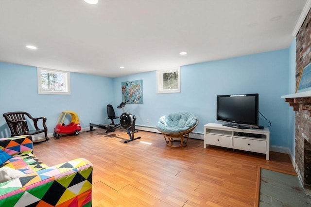exercise area featuring wood finished floors, a fireplace, recessed lighting, a baseboard heating unit, and baseboards