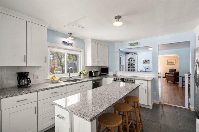 kitchen with a center island, a sink, tasteful backsplash, a breakfast bar area, and white cabinetry