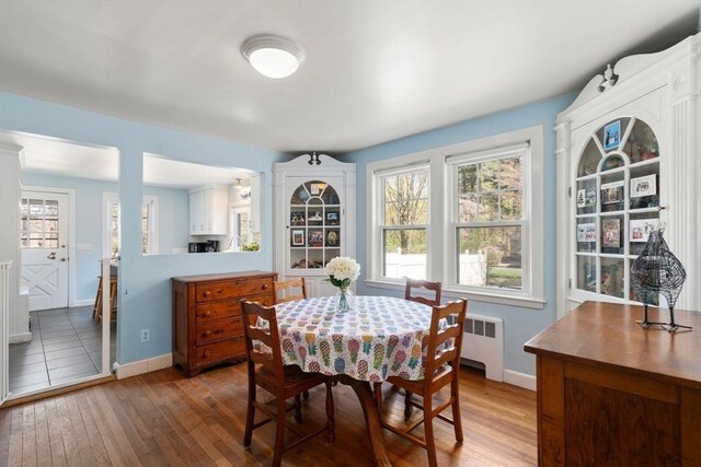 dining space with wood-type flooring, baseboards, and radiator heating unit