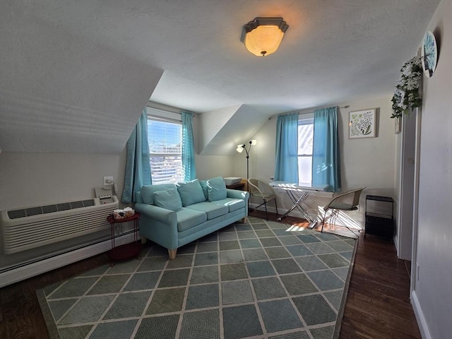 sitting room with wood finished floors, baseboards, a wall mounted AC, lofted ceiling, and a textured ceiling