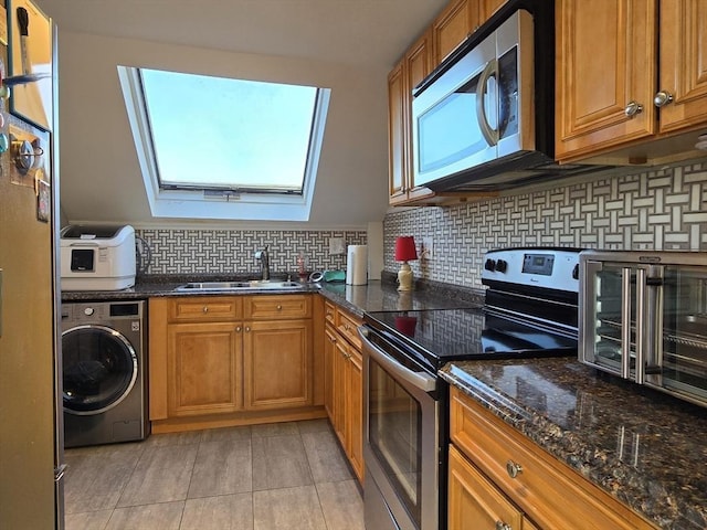 kitchen with brown cabinets, a sink, washer / clothes dryer, backsplash, and stainless steel appliances