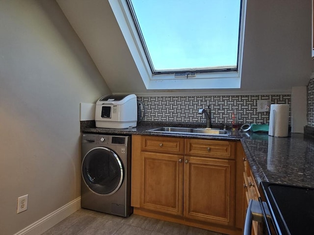 washroom with baseboards, washer / dryer, a skylight, laundry area, and a sink