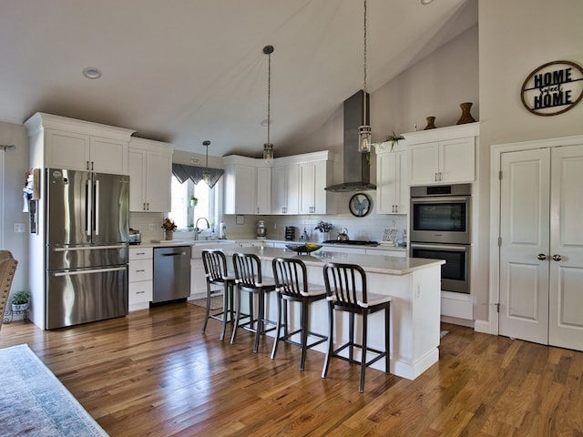 kitchen with high vaulted ceiling, dark wood-type flooring, stainless steel appliances, and wall chimney exhaust hood