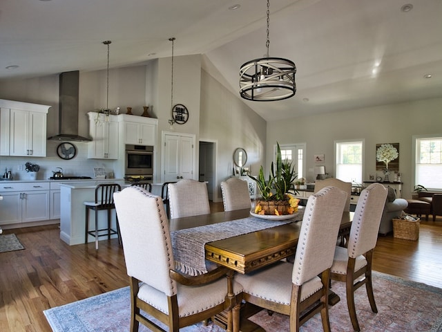 dining area with dark wood-type flooring, high vaulted ceiling, and a chandelier