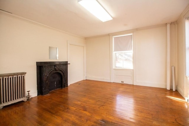 unfurnished living room featuring hardwood / wood-style floors, radiator heating unit, a fireplace, and ornamental molding