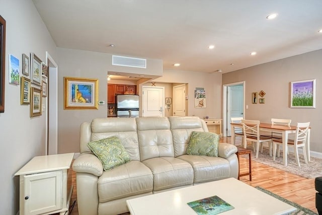 living area with light wood finished floors, visible vents, and recessed lighting