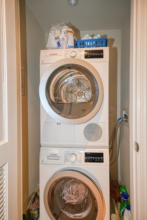 clothes washing area featuring stacked washer and dryer and laundry area