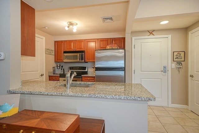 kitchen with visible vents, appliances with stainless steel finishes, a sink, light stone countertops, and a peninsula