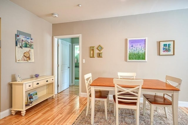 dining space with baseboards and light wood-style floors