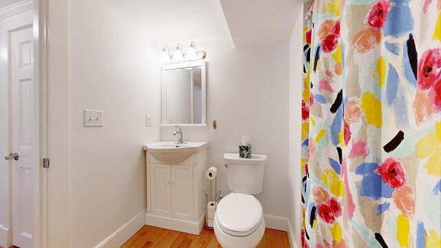 bathroom with hardwood / wood-style flooring, vanity, a shower with shower curtain, and toilet