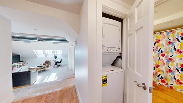 laundry room with hardwood / wood-style floors and stacked washer / drying machine