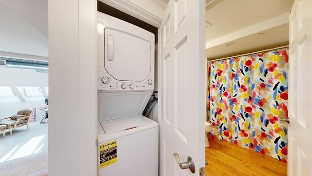 laundry area featuring hardwood / wood-style floors and stacked washer / drying machine