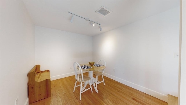 dining room with hardwood / wood-style floors and track lighting