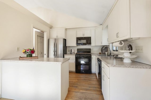 kitchen with a sink, black appliances, white cabinets, vaulted ceiling, and light wood-type flooring