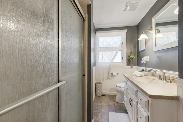 bathroom with vanity, a shower stall, wainscoting, and toilet