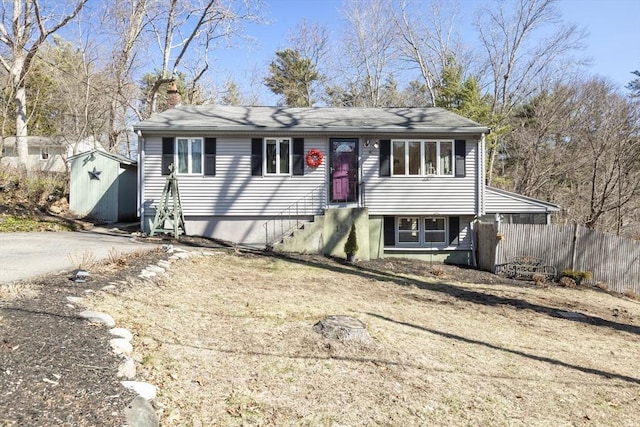 view of front of house featuring dirt driveway, fence, a storage shed, an outdoor structure, and a chimney