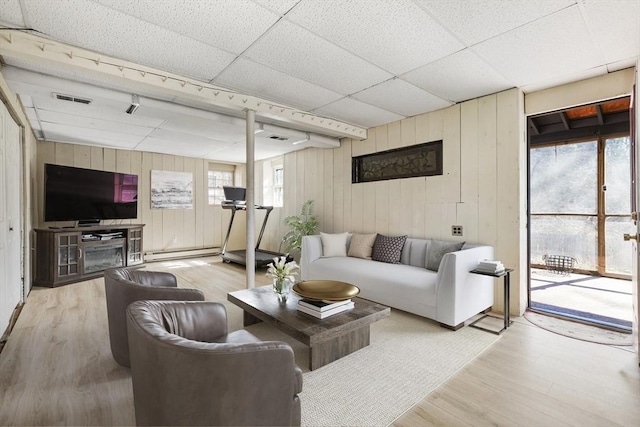 living room featuring a baseboard heating unit, wood finished floors, visible vents, and a paneled ceiling