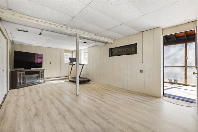 basement with visible vents, a drop ceiling, a baseboard heating unit, and wood finished floors