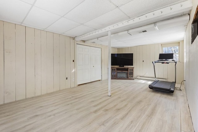 workout area featuring a drop ceiling, baseboard heating, visible vents, and wood finished floors