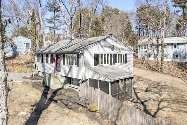 view of front facade featuring concrete driveway, fence, a sunroom, and a chimney