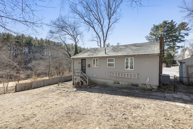 rear view of property featuring a chimney and fence