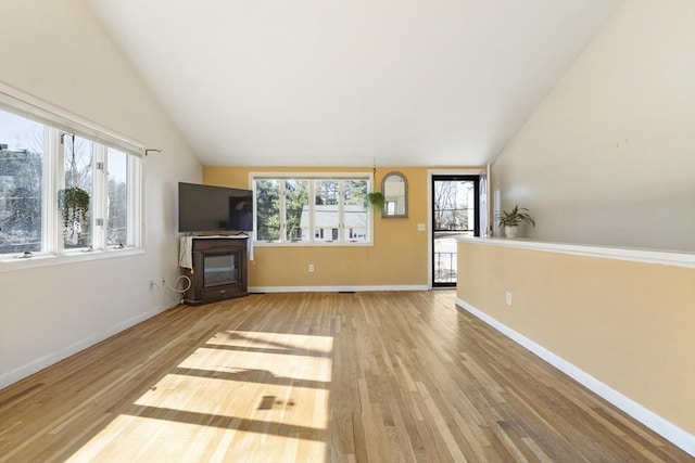 unfurnished living room featuring a wealth of natural light, lofted ceiling, and wood finished floors