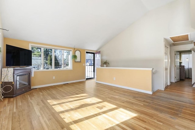 unfurnished living room featuring baseboards, light wood finished floors, and high vaulted ceiling